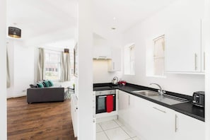 A modern apartment with a living room, kitchenette, and a view of the city. - The Newhall Loft | Spacious Private Duplex in JQ (West Midlands)