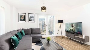 Ein modernes Wohnzimmer mit einem Ecksofa, einem Flachbildfernseher, einem Couchtisch und einer Stehlampe.