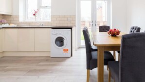 Una cocina moderna con lavadora incorporada, un comedor con mesa y sillas, y un reloj de pared grande.