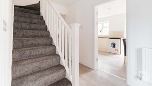 Una escalera conduce a un área de lavandería con lavadora y secadora.