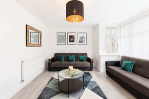 Een moderne woonkamer met een bank, een salontafel en ingekaderde foto’s aan de muur.