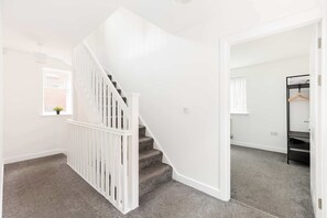 Eine Treppe mit weißen Geländern, die zu einer Zwischenebene führt.
