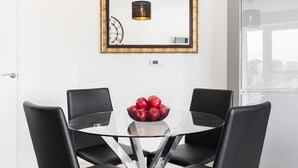 A dining area with a glass table, black chairs, and a bowl of red apples. - St Lukes Retreat | Modern Top Floor City Escape (West Midlands)
