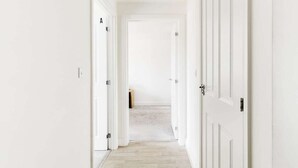 A corridor with white doors, a wooden floor, and a carpeted area at the end. - St Lukes Retreat | Modern Top Floor City Escape (West Midlands)