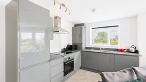 A modern kitchen with a built-in oven, microwave, and a large window providing a view of greenery. - St Lukes Retreat | Modern Top Floor City Escape (West Midlands)