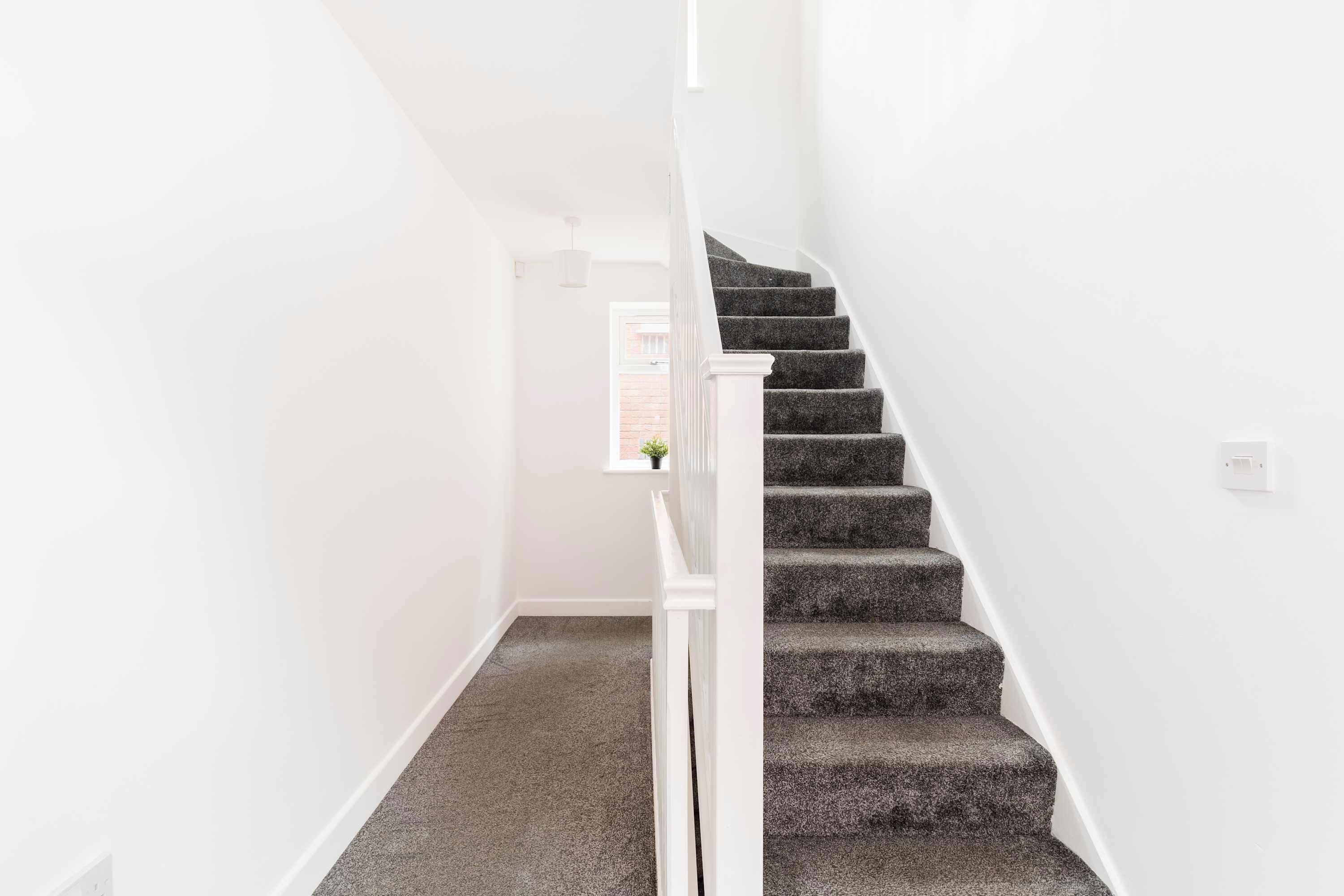 A staircase with carpeted steps and white walls.