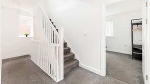 A staircase with white railings leading to a landing. - Birmingham Estate | Gather Stay & Celebrate (Winson Green)