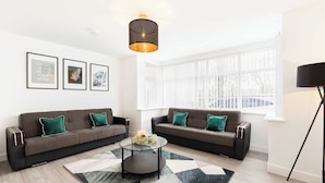 A modern living room with two sofas, a coffee table, and a large window. - Birmingham Estate | Gather Stay & Celebrate (Winson Green)