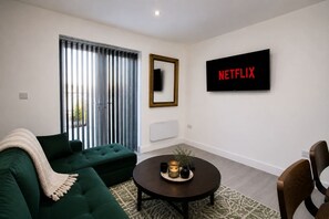 A modern living room with a green sofa, a coffee table, and a TV displaying 'NETFLIX'. - Cardiff Bloc 2 | Couple & Groups | Large Balcony (Rumney)