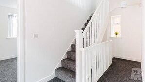 Un escalier avec des rampes blanches et des marches recouvertes de moquette.