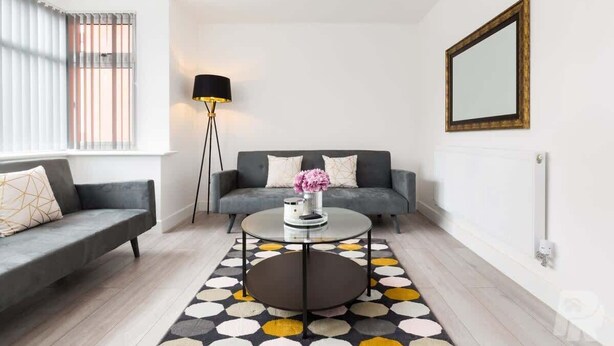 Un salon moderne avec un canapé, une table basse, un lampadaire et un tapis à motifs.