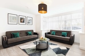 A modern living room with two sofas, a coffee table, and framed pictures on the wall. - Birmingham Estate | Gated | Built For Large Groups (Winson Green)