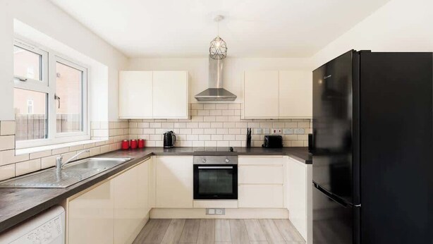 Een moderne keuken met witte kasten, een zwarte koelkast en een inbouwoven.