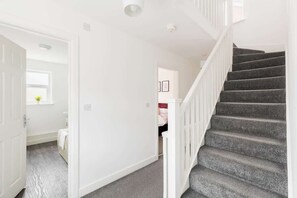 A staircase with carpeted steps and white railings, leading to a landing with a door. - Birmingham Estate | Detached Home for Togetherness (Birmingham)
