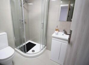 A modern bathroom with a glass-enclosed shower, a white toilet, and a sink with a mirror above it. - Cardiff Bloc | The Ultimate Group Stay for 10 (Rumney)