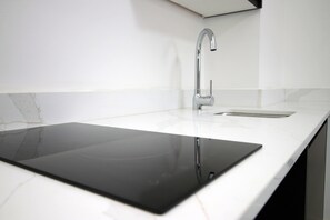 A modern kitchen with a sleek black countertop, a stainless steel faucet, and a white marble backsplash. - Cardiff Bloc | The Ultimate Group Stay for 10 (Rumney)