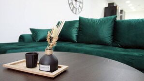 Un salon moderne avec une table ronde de couleur marron foncé, un vase noir contenant des plantes séchées et une tasse noire posée sur un plateau en bois.