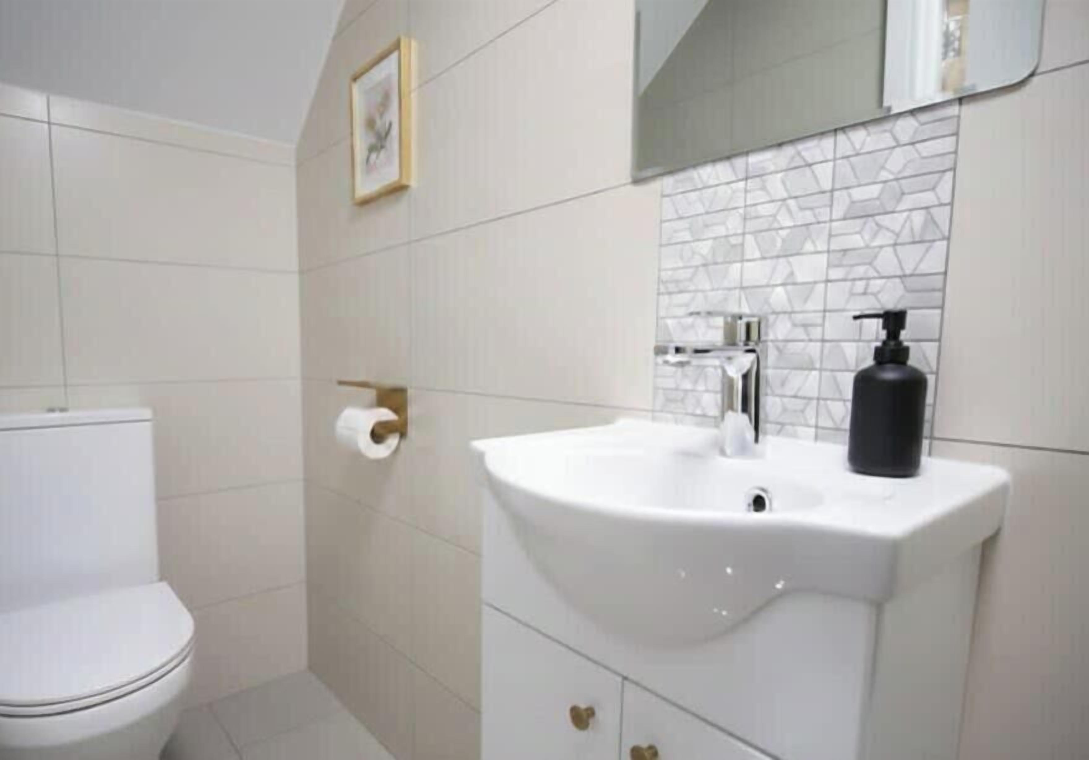 A bathroom with a toilet, a sink with a mirror above it, and a toilet paper holder on the wall.