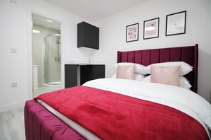 A bedroom with a large bed, a walk-in shower, a black cabinet, and three framed pictures on the wall. - Cardiff Bloc | The Ultimate Group Stay for 10 (Rumney)