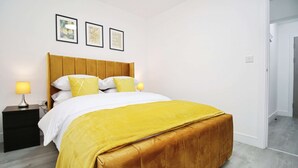 Une chambre à coucher bien rangée, avec un lit, des tables de chevet et des tableaux encadrés accrochés au mur.