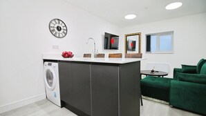 Une cuisine moderne dotée d’un lave-linge encastré, d’un îlot central et d’un canapé vert.