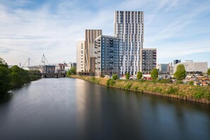 Una moderna riva fluviale urbana con grattacieli, un ponte e un fiume tranquillo.
