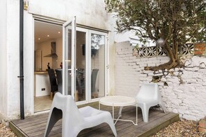 Patio aperto con tavolo e sedie, un albero e un muro in mattoni.