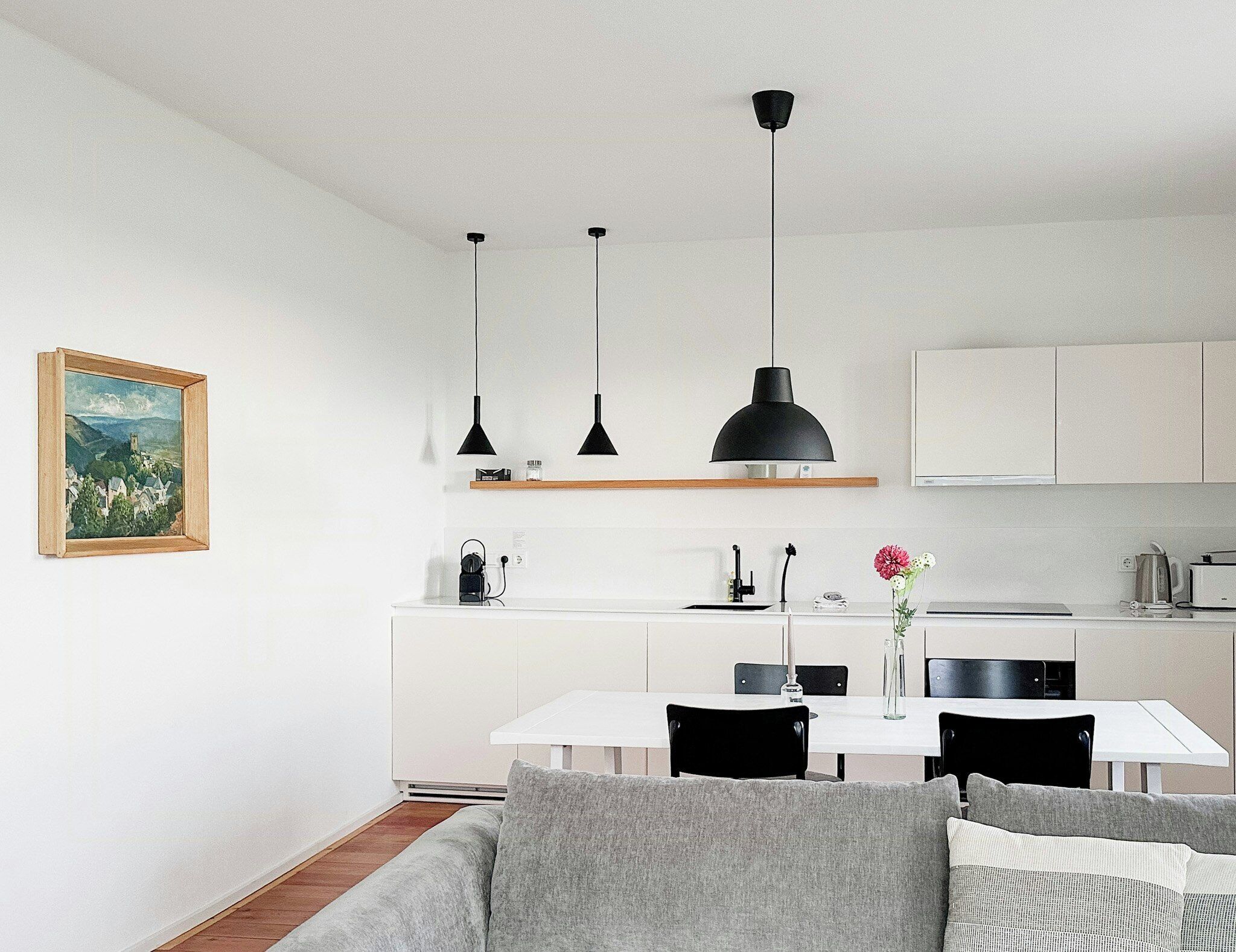 A modern kitchen with white cabinets, a dining table with chairs, and pendant lighting.