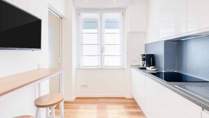 Una cocina moderna con armarios blancos, una estufa negra y una ventana con persianas.