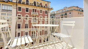Un balcón con barandilla de metal blanco y una mesa plegable blanca.