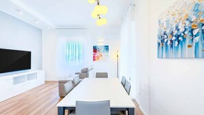 Una sala moderna con televisión de pantalla plana, una mesa de comedor y un sofá.