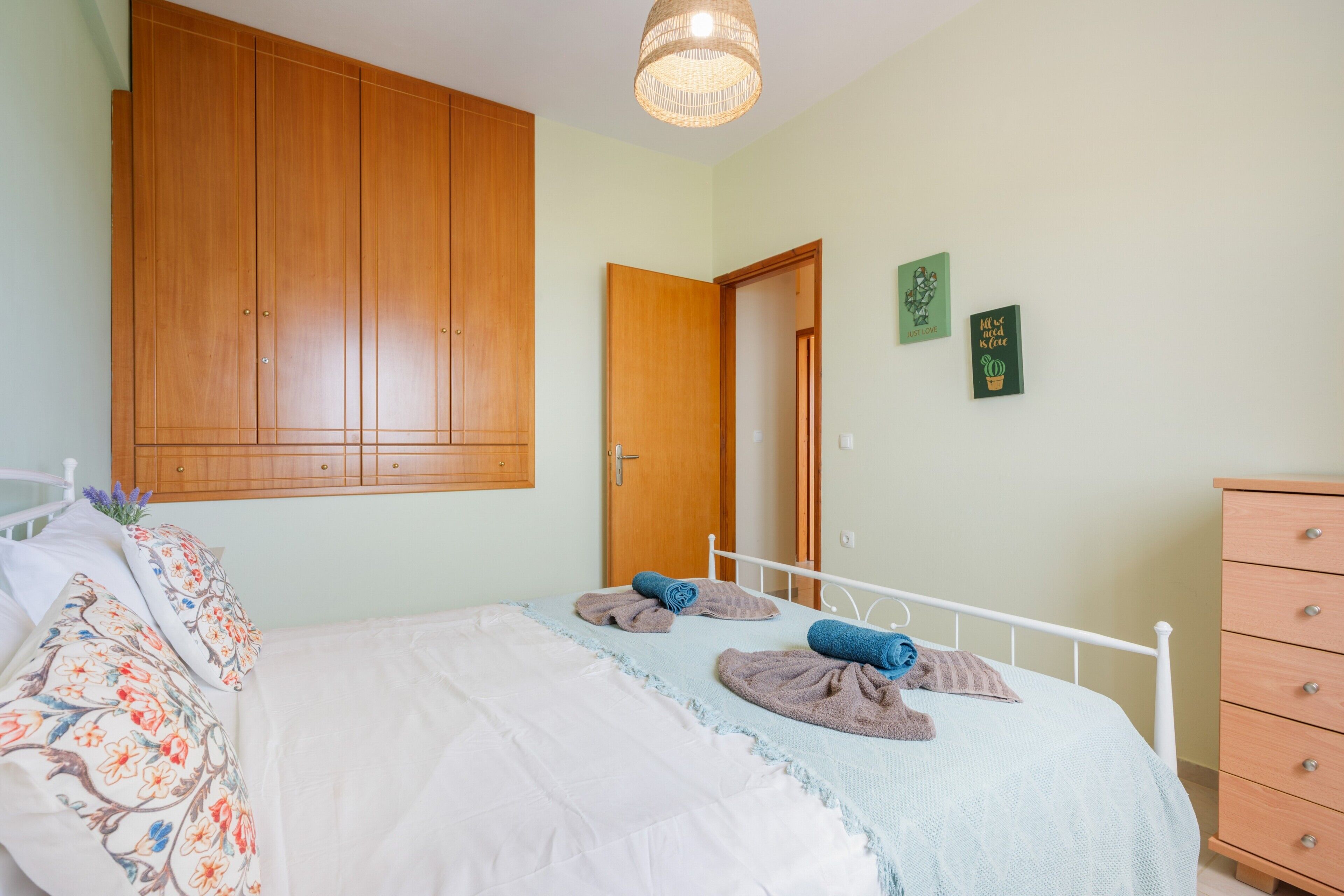 A bedroom with a bed, a wardrobe, a dresser, and a door.