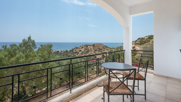 A balcony with a table and chairs, offering a view of the sea and hills. - Panoramablick auf das Libysche Meer im SeaCrete House! (Keratokampos)