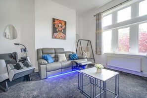 A modern living room with a grey sofa, a small table, and a swing chair. - 12GH - Soothing & Cosy Stay (West Yorkshire)