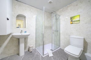 A bathroom with a glass-enclosed shower, a sink, a toilet, and a mirror. - Comfortable and Grand Stay in City Centre (West Yorkshire)