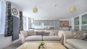 En moderne stue med sofa, sofabord og udsigt til køkkenet.