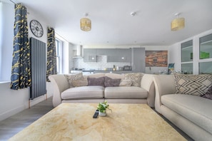 A modern living room with a sofa, coffee table, and a view into the kitchen. - Comfortable and Grand Stay in City Centre (West Yorkshire)