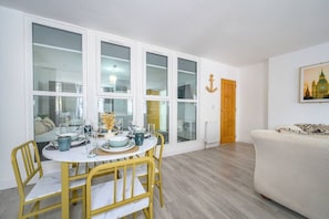 A dining area with a round table, chairs, and a view through large windows. - Comfortable and Grand Stay in City Centre (West Yorkshire)