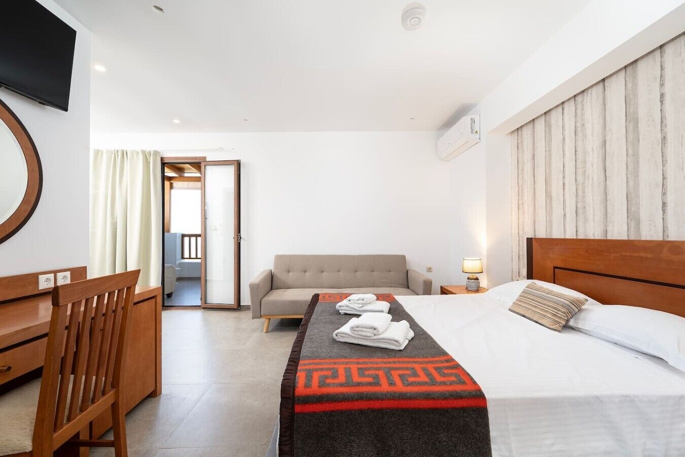 Une chambre d’hôtel avec un lit, un canapé, un bureau et une télévision.