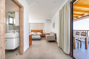 Ein Hotelzimmer mit Bett, Nachttisch, Stuhl und einem Balkon mit Tisch und Stühlen.