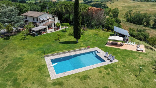 Una propiedad residencial con piscina, un patio cubierto y vistas al campo circundante.
