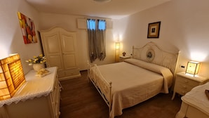 Un dormitorio con cama, mesitas de noche, cómoda, armario y ventana con cortinas.