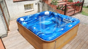 Un jacuzzi de madera con tapa transparente, situado en una terraza de madera.
