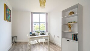 Une pièce comprenant une table à manger, deux chaises, une bibliothèque et une fenêtre donnant sur un paysage agréable.
