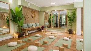 Ein Yoga-Studio mit Holzböden, grünen Matten und einer Holzbank mit Kissen.