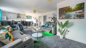 Un salon moderne comprenant un canapé, une table basse et un coin repas avec des chaises.