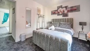 Une chambre à coucher comprenant un lit, une table de chevet, un miroir et une œuvre d’art murale.