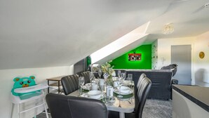 A dining area with a table set for four, a child’s play table, and a green accent wall. - Stylish Home for 6 in West Yorkshire (West Yorkshire)