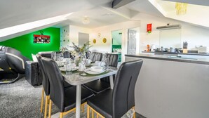 A modern dining area with a high ceiling, a green accent wall, and a kitchen with a countertop. - Stylish Home for 6 in West Yorkshire (West Yorkshire)
