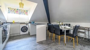 A compact kitchen with a washing machine, a dining area with a table and chairs, and a decorative ceiling light. - Stylish Home for 6 in West Yorkshire (West Yorkshire)